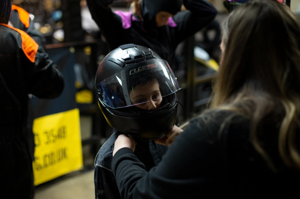 Parent strapping kids go karting helmet